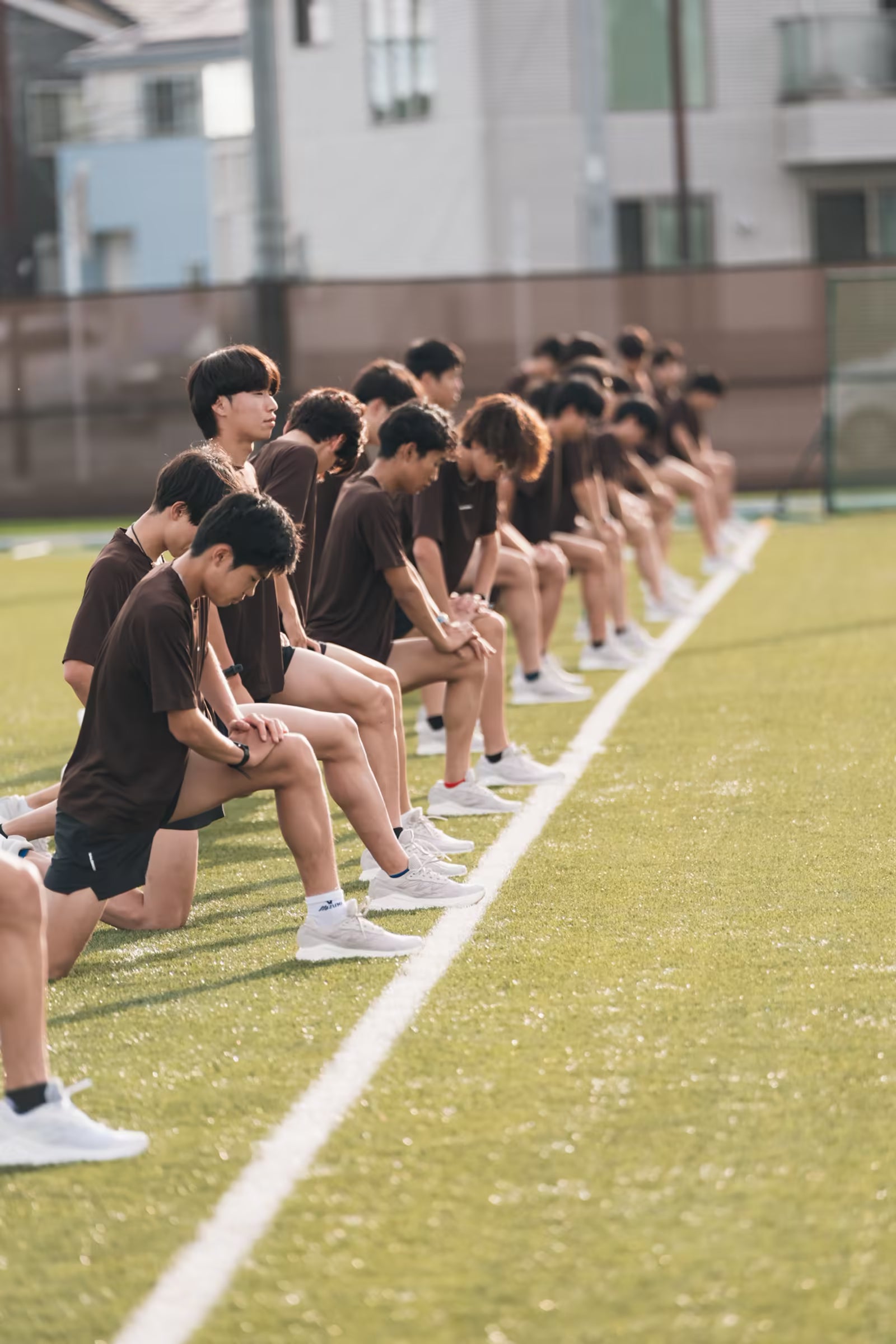 グラウンド脇に並び練習を見守る選手たち