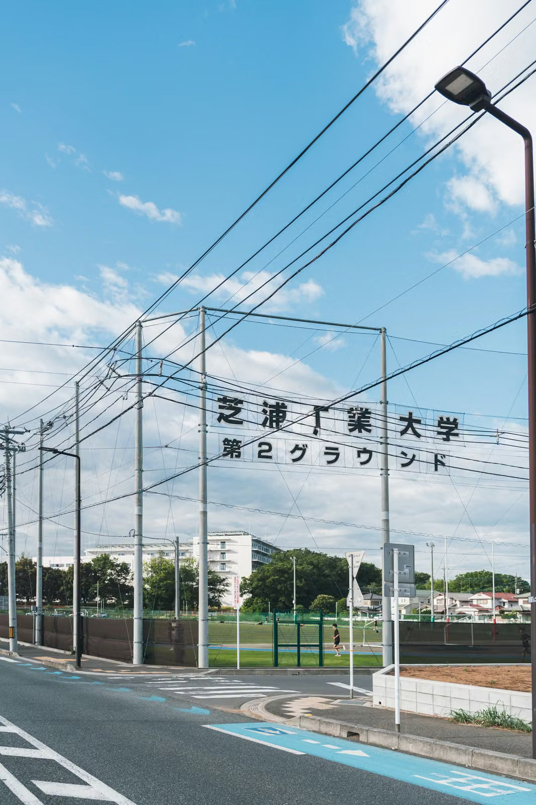 青空の下の芝浦工業大学グラウンドの看板